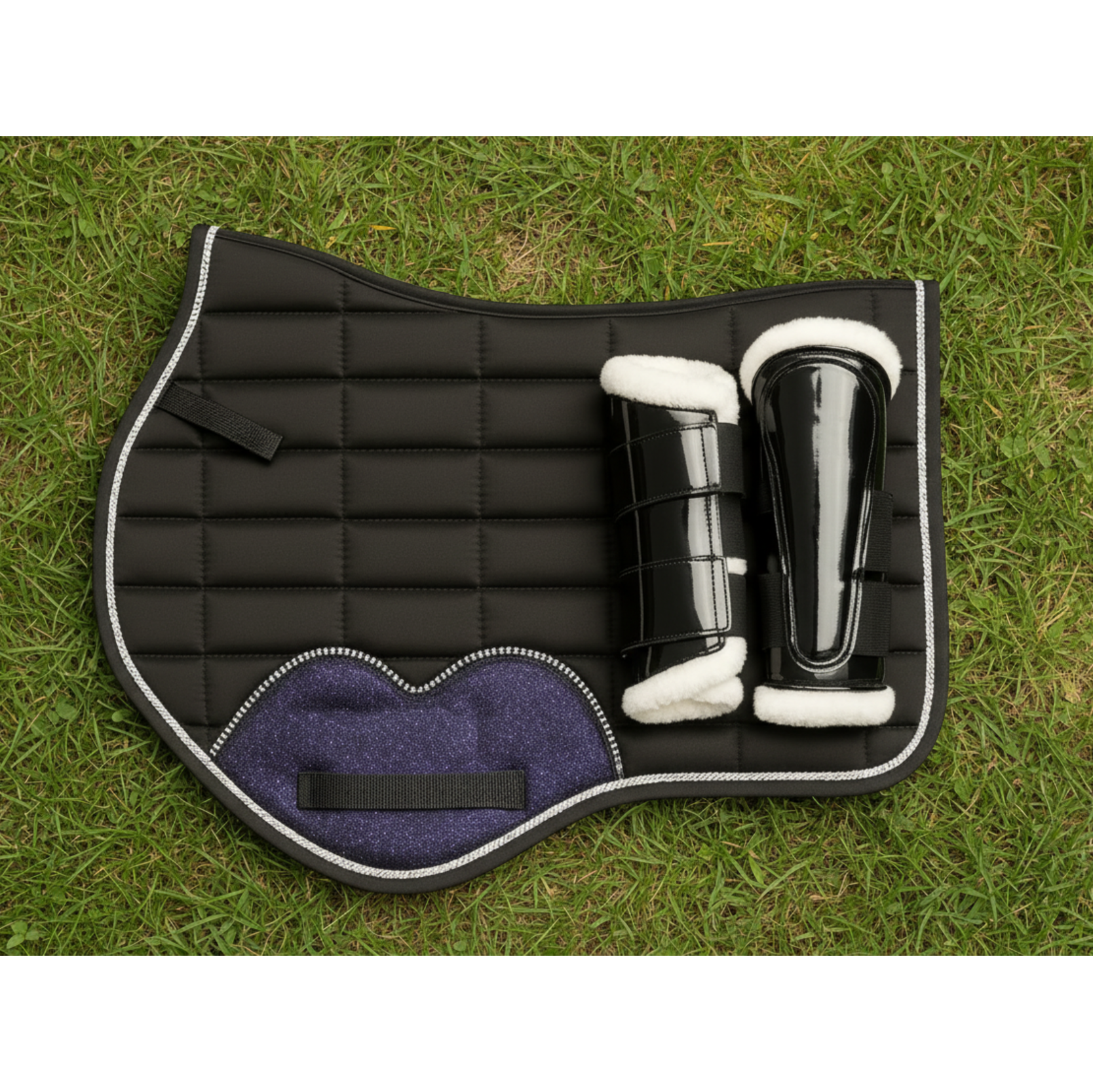 Black quilted saddle pad with white interior on grass
