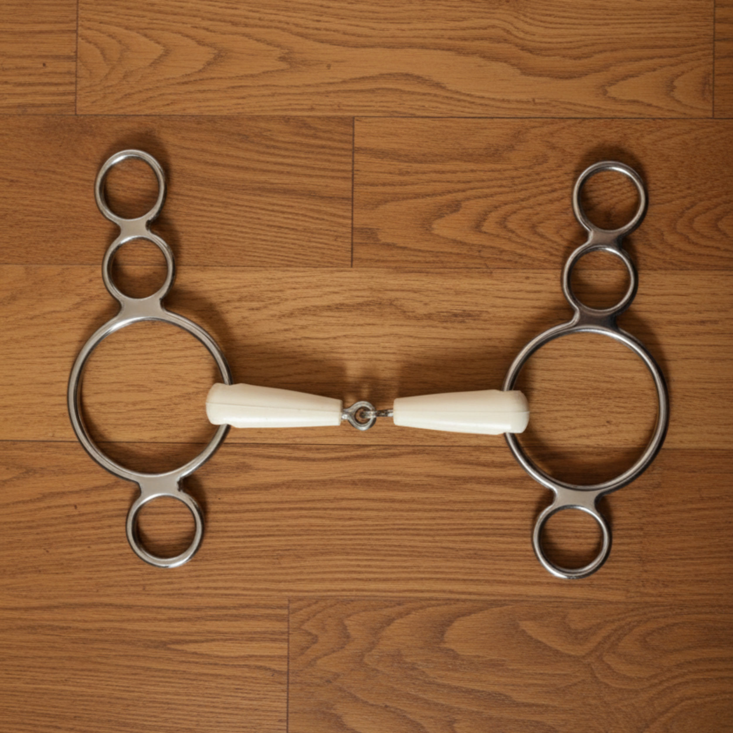 Metal horse bridle bit with bone handle on a gray background